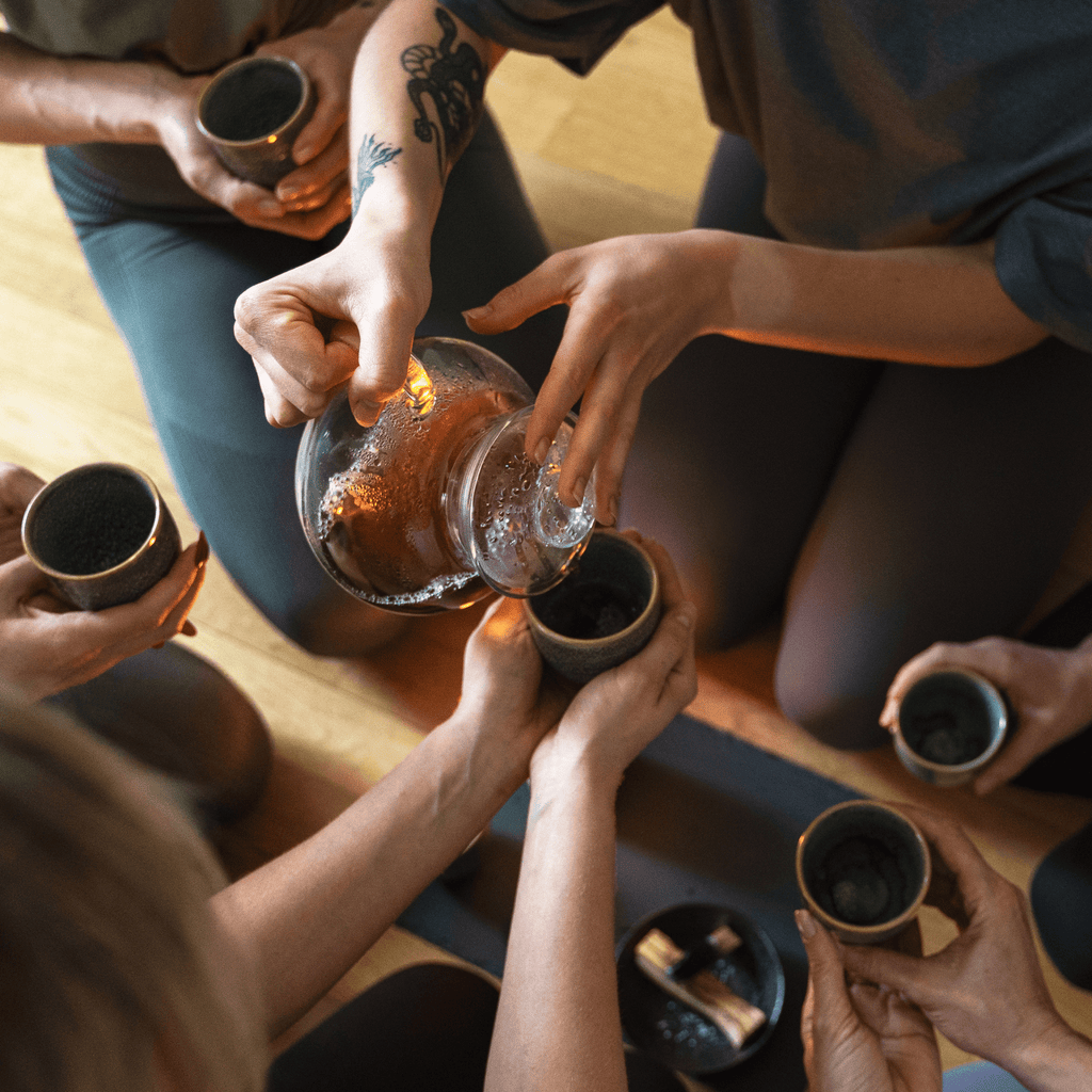 pouring tea in tea cups at yoga retreat Planting Organics